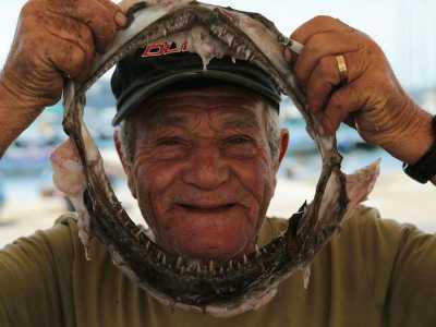Il pescatore Oronzo Lagioia mentre gioca con le fauci di uno squalo